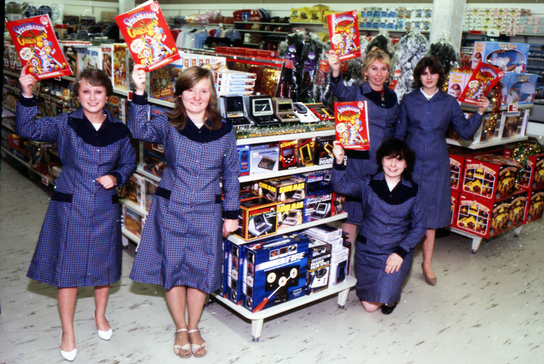 Colleagues show off the latest, great, evermore spectacular Woolworths Christmas Catalogue for 1983. The new HR Director, Don Rose, was very critical of the outfits that Woolworth expected them to wear, calling them uncomfortable, unflattering overalls when they deserved smart, comfortable uniforms that they would be proud to wear. He made updating staff attire a top priority as the store estate was regenerated.