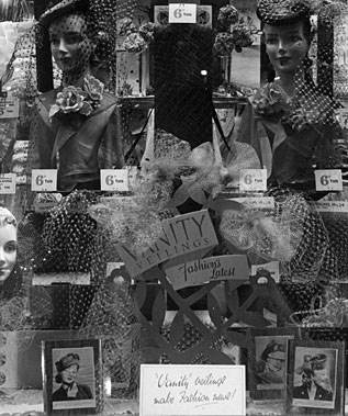 A window display of Vanity Veilings in Chiswick High Road, a bargain range concocted by Woolworth's Buyer Herbert Cue to exploit bolts of fancy fabric that he routinely acquired from London's leading fashion houses. Shoppers could snap up a bargain hat or accessory that would cost £1 or more made up in a department store for a single sixpence, one fortieth of that price and give their hats a new lease of life