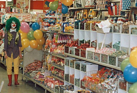 Saturday Assistant Julia Brown standing in front of the Pic'n'Mix sweet counter at the Woolworths store in Camberley, Surrey, UK on Fancy Dress Day in Summer 1987